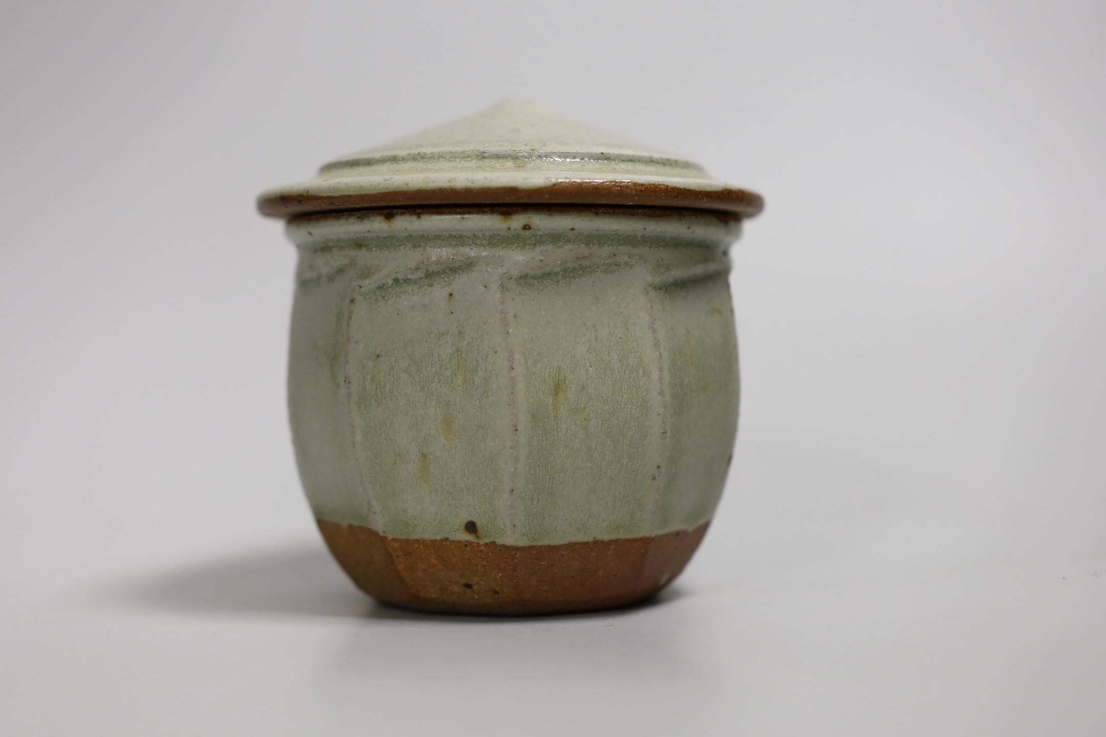 Richard Batterham (1936 – 2021), a cut sided stoneware jar and pointed cover with sage coloured glaze. 10.5cm high